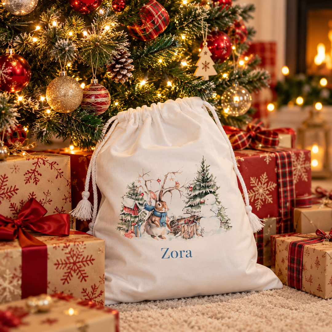 Personalised Christmas sack with watercolour bunny scene and name, drawstring with tassels, under a Christmas tree with presents