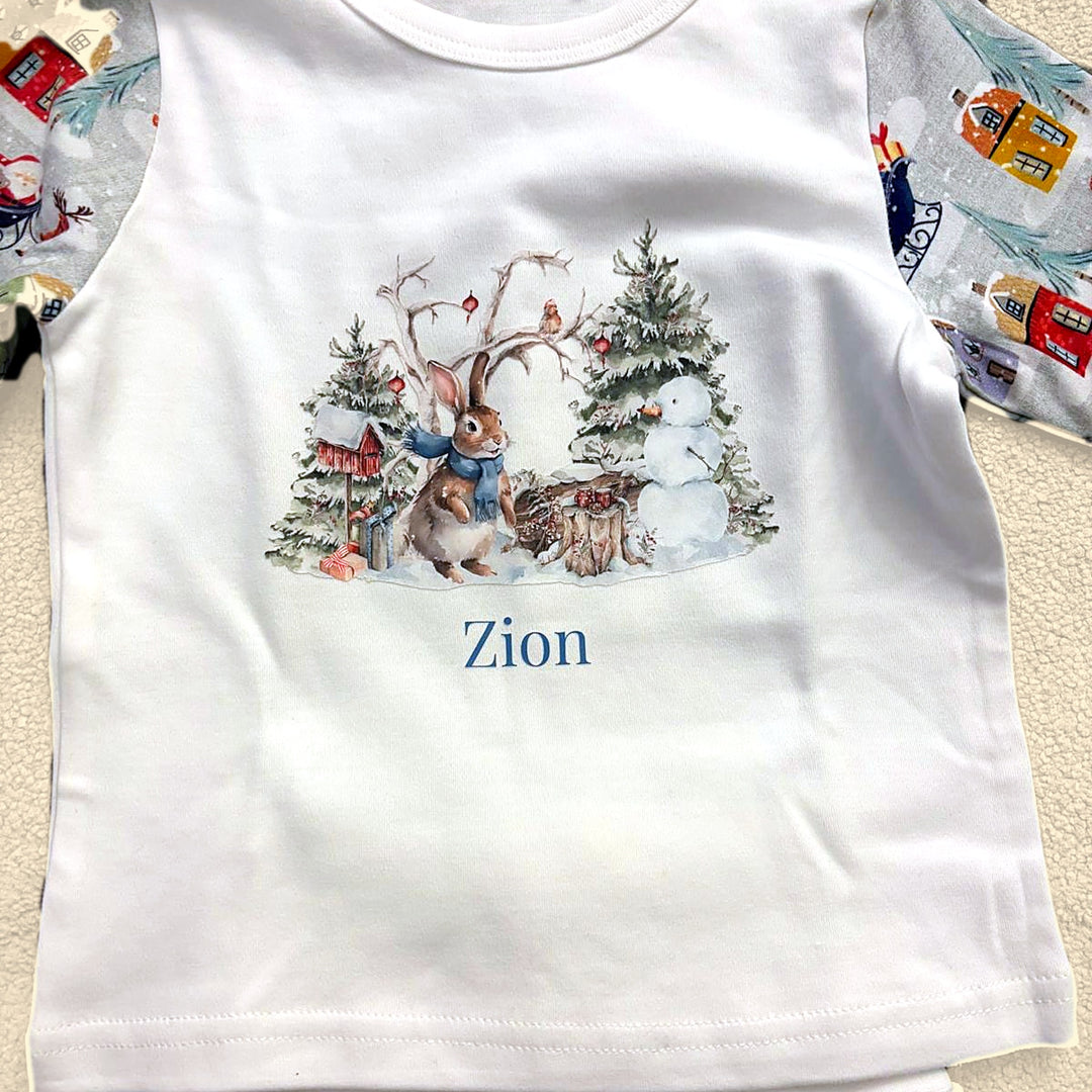 Close-up of personalised Christmas pyjama top with watercolour bunny, snowman and trees and the name printed in blue