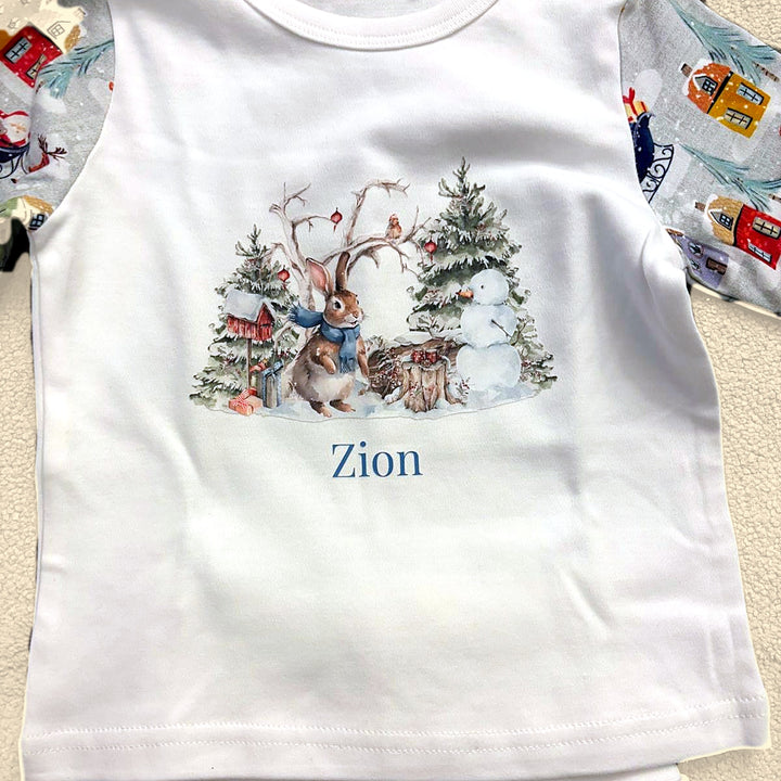 Close-up of personalised Christmas pyjama top with watercolour bunny, snowman and trees and the name printed in blue